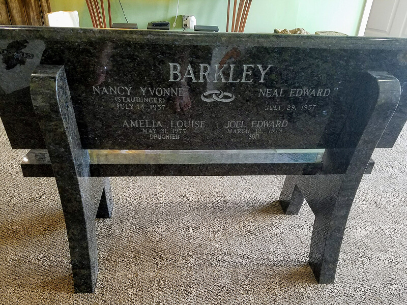 Polished dark green granite memorial bench engraved with a family name