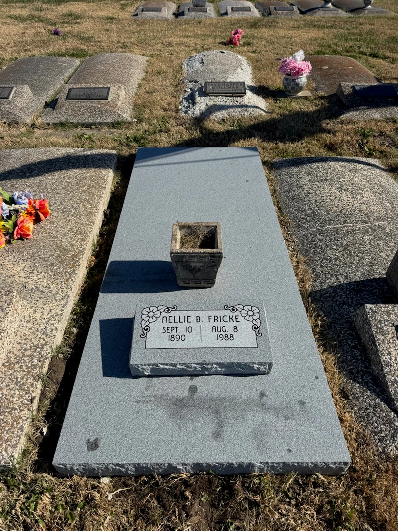 Grey granite ledger with a small carved marker and a stone vase