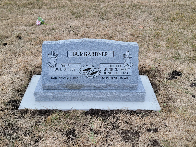 Grey granite slant memorial carved with praying hands and wedding rings