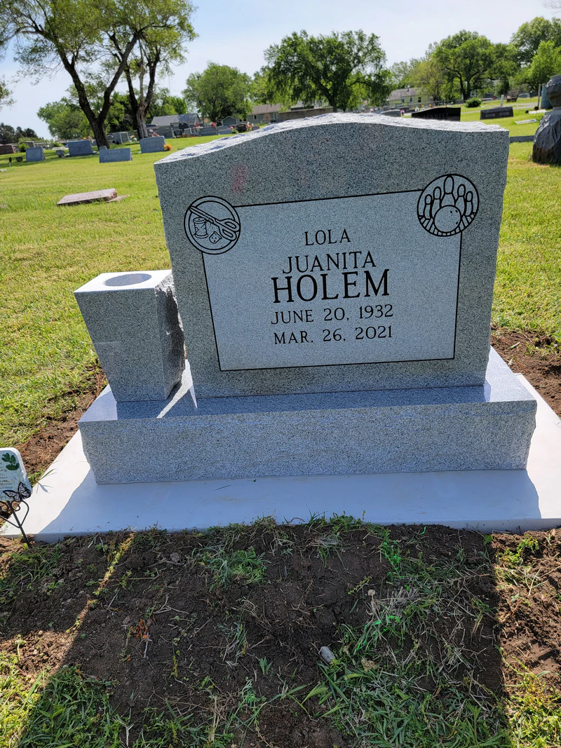 Grey granite upright headstone with carved emblems and a granite vase, set on a new foundation in a Kansas cemetery