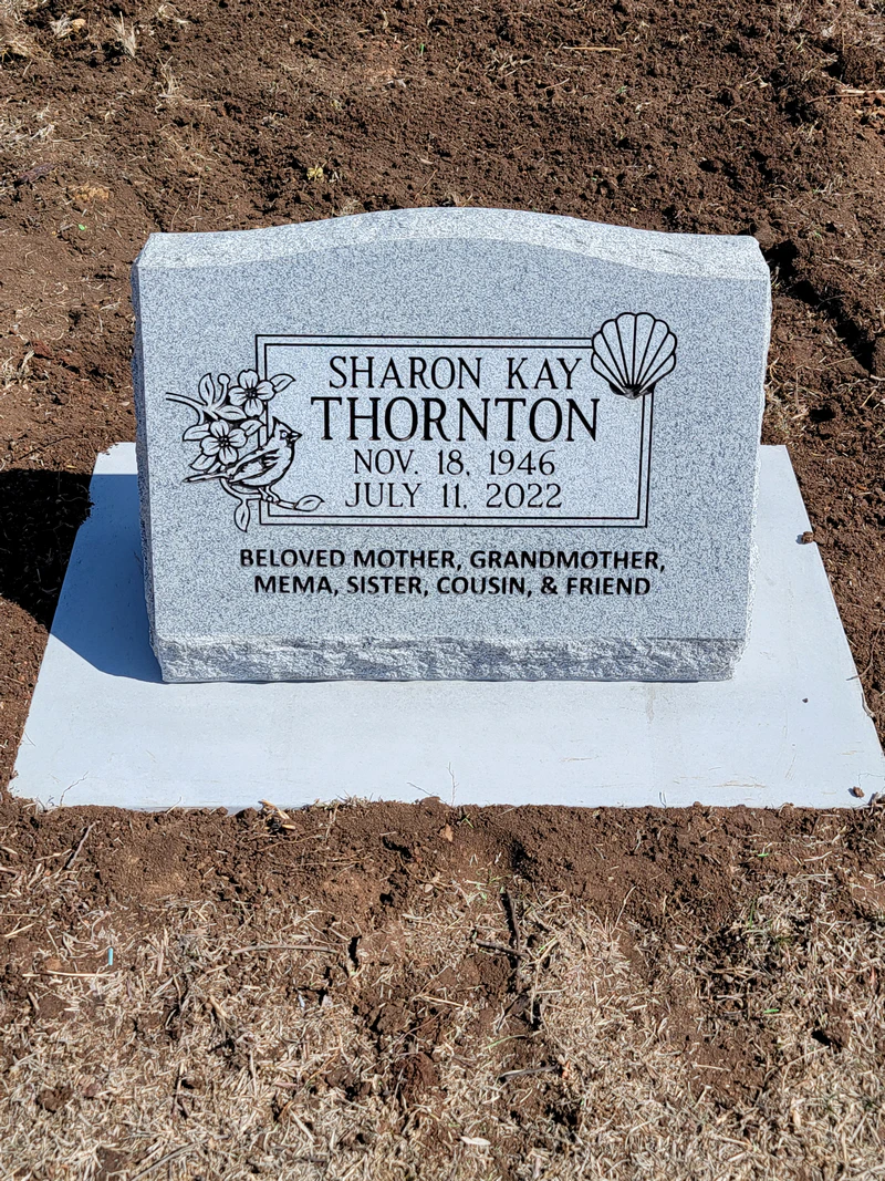 Grey granite upright headstone with a carved cardinal and dogwood blossoms